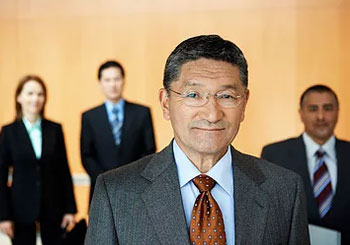 man in glasses and suit with people in background 